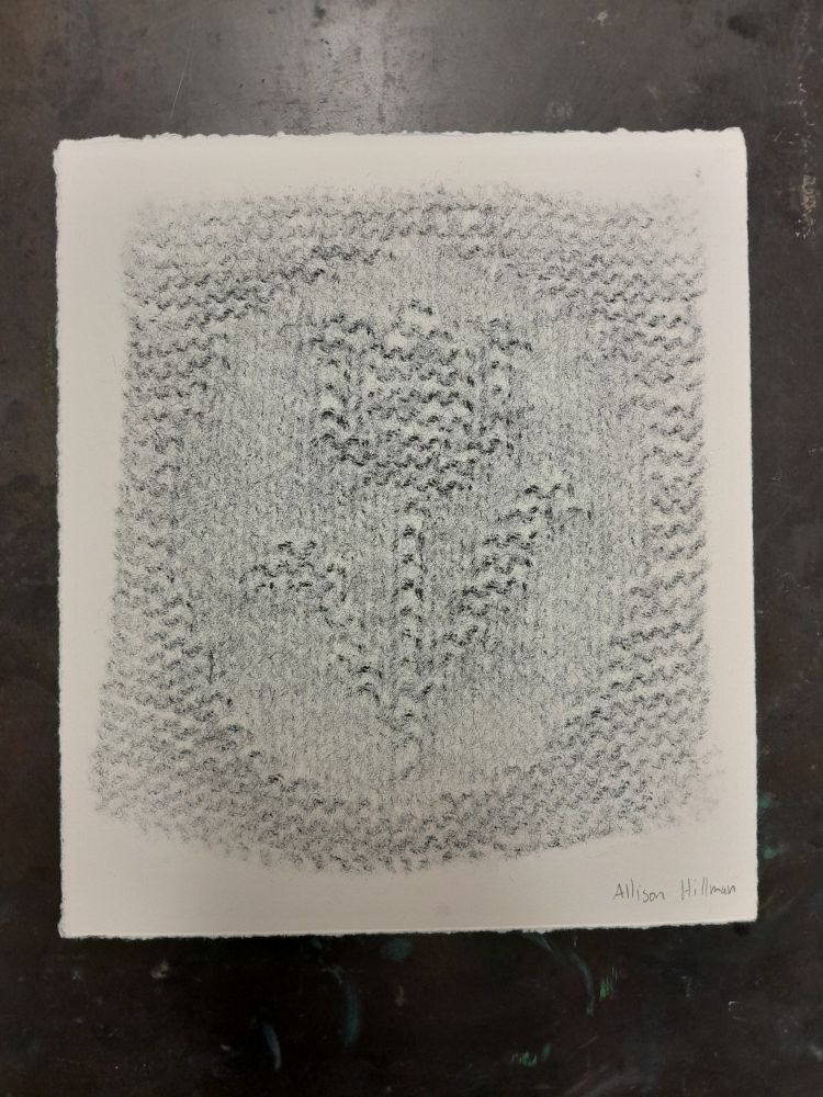 Black and white imprint of a knitted swatch containing a flower motif