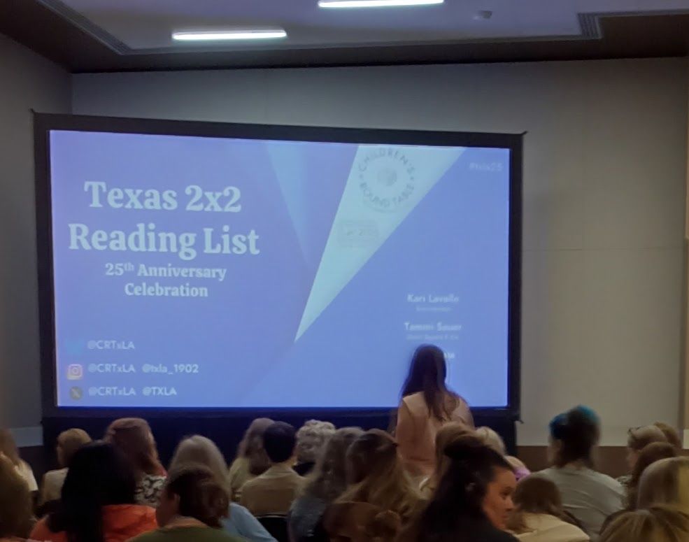 A large screen in a conference room with an audience.