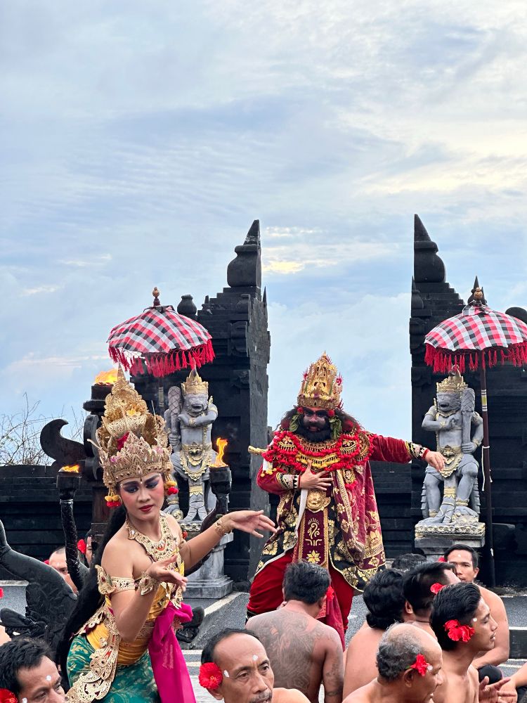 A woman in the foreground and a Balinese demon king in the background at the uluwatu kecak and fire dance