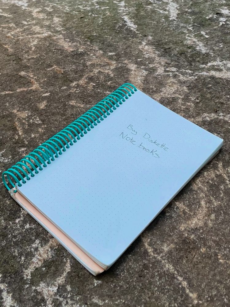 a spiral bound notebook on a rock. the open page says “buy diskette notebooks”