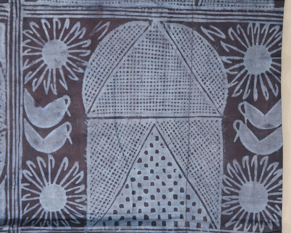 Blue textile featuring birds, flowers and a central building in a lighter shade of blue.