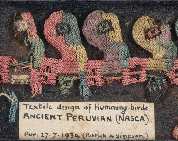 Fragment of coloured embroidery with old handwritten label saying Textile design of Humming-birds, Ancient Peruvian (Nasca)