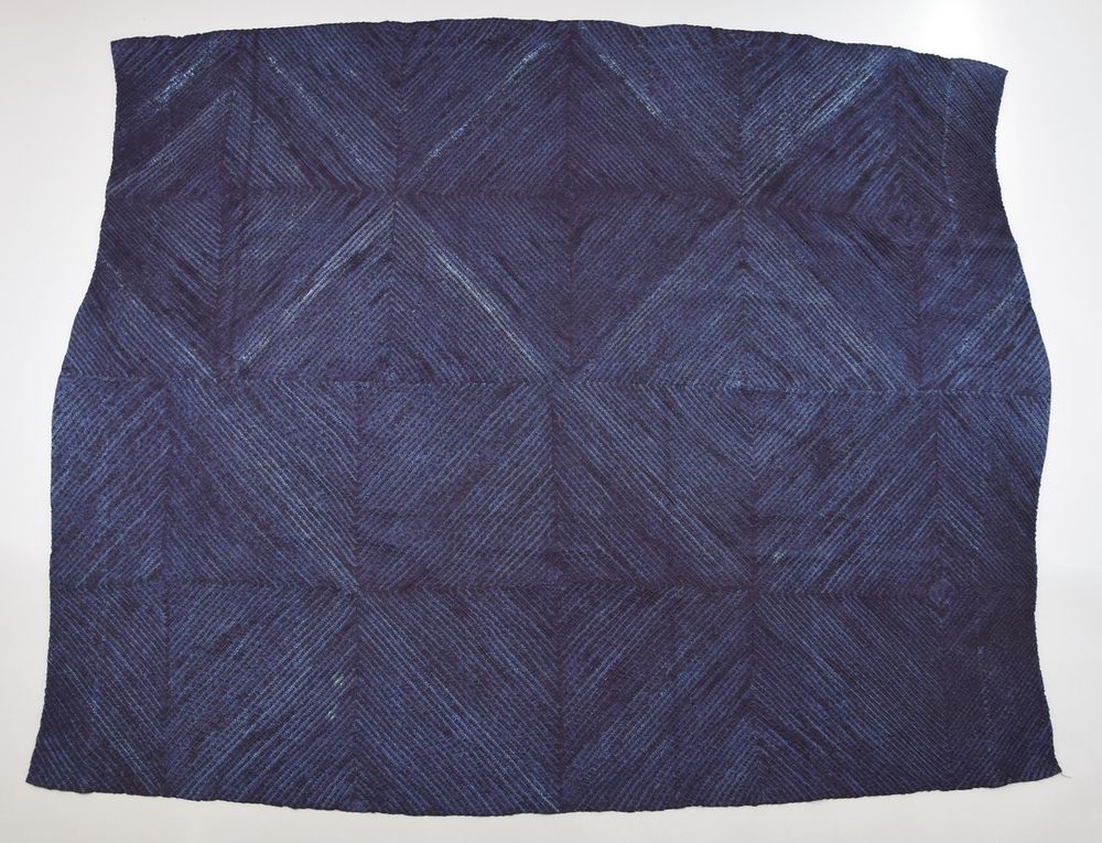 Dark blue textile showing a repeated diamond pattern in varying shades of blue.