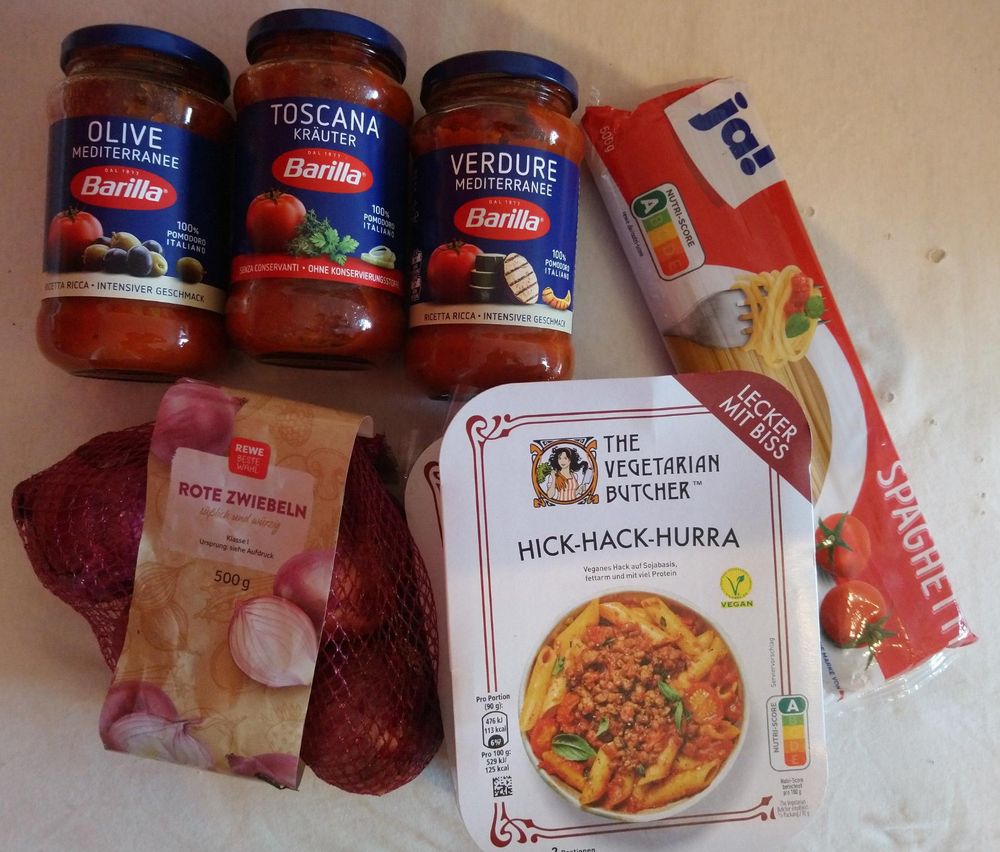 Foto von Roten Zwiebeln, einer Packung Spaghetti, Packungen von Hick-Hack-Hurra und drei Gläsern mit Tomaten-Sauce der Marke Barilla:

Olive Mediteranee von Barilla,
Toscana Kräuter von Barilla,
Verdure Mediteranee von Barilla.