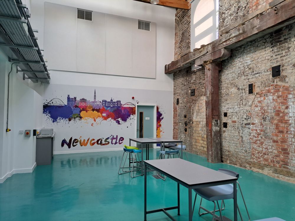 One of the rooms in the UTC building with bare brick wall on one side and white covered walls on the others.