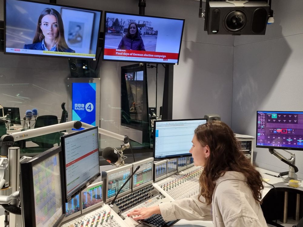 Student sits at mixing desk in front of studio