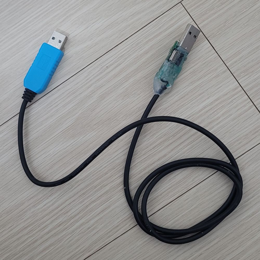 Picture shows a cable with two USB plugs at both ends, with one side being blue and the other side being molded out of hot glue and containing a green circuit board inside.