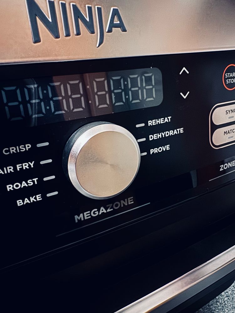 Nahaufnahme (Teilfoto ) einer Heissluftfritteuse. Schwarz mit Silbernen Elementen. Marke: Ninja. 