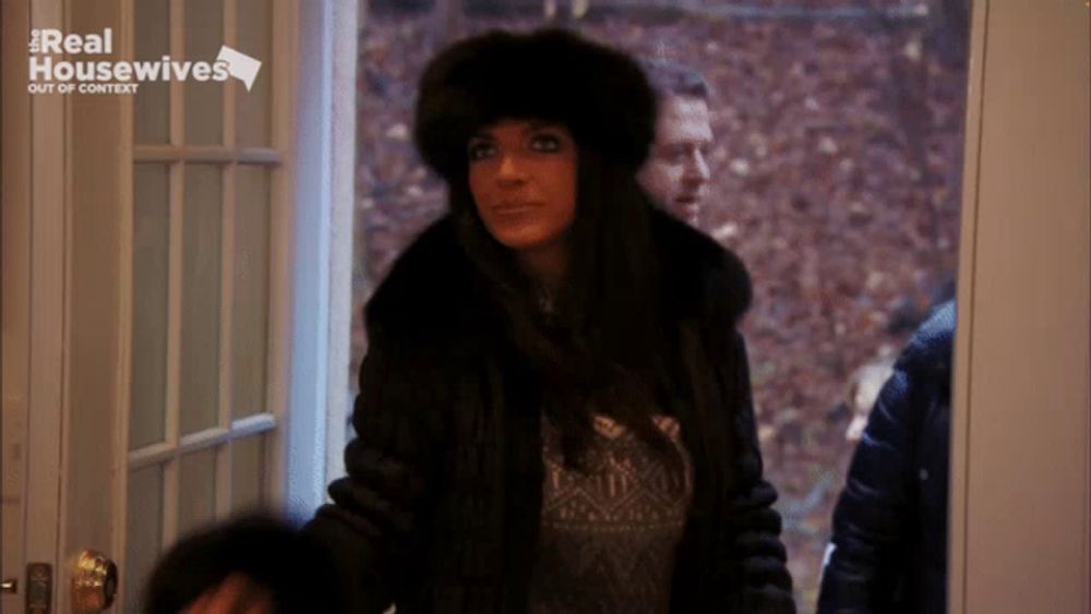 a woman in a fur coat stands in front of a real housewives logo