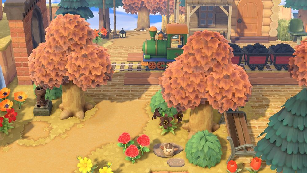acnh fake train station :green train, coal minecarts, trees, string lights, villagers house, fake storefronts attached to villagers house, fake brick, fake train tracks, fake wooden boards, flowers, 