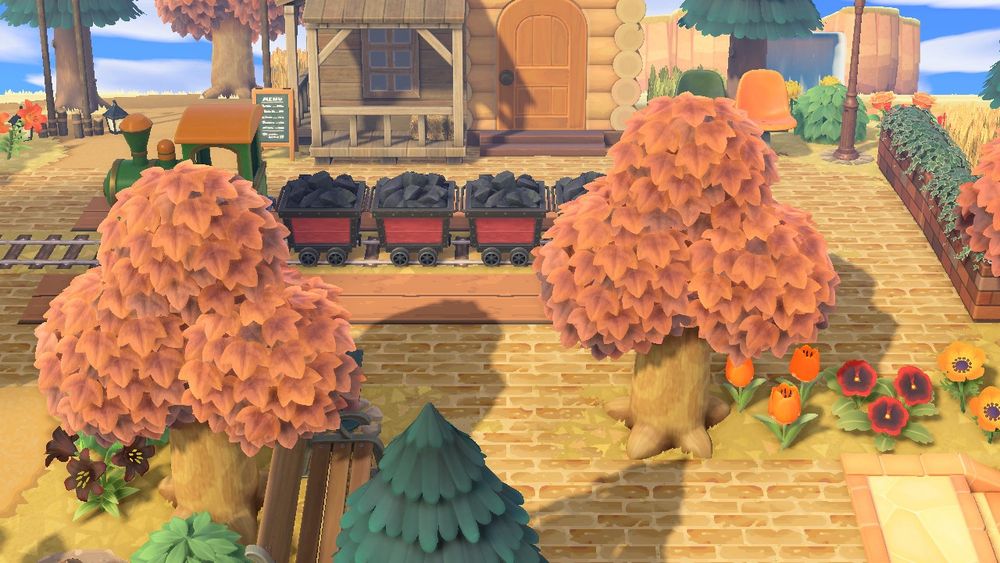 acnh fake train station :green train, coal minecarts, trees, string lights, villagers house, fake storefronts attached to villagers house, fake brick, fake train tracks, fake wooden boards, flowers