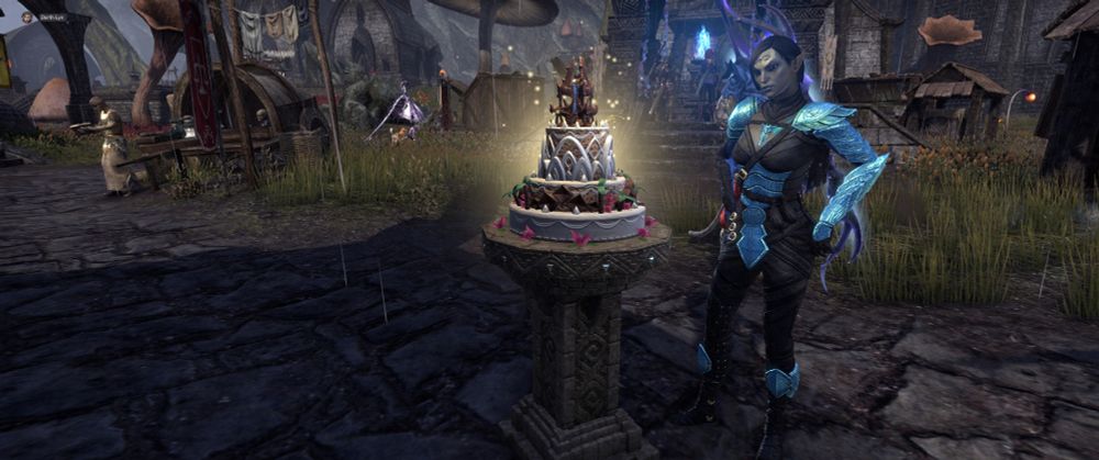 my main, Gilli, she's a dunmer wearing the black and blue dyed elven hero costume. Next to her is the 2025 ESO Birthday cake