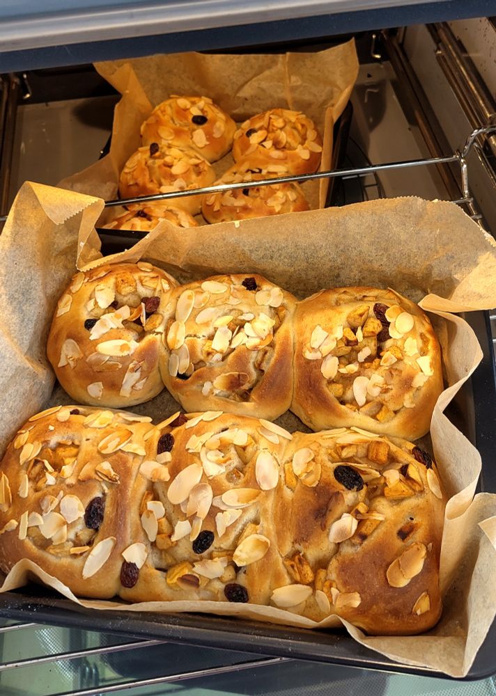 アップルロール焼き菓子が焼き上がってオーブンから出たところ。２つの四角い焼き型にそれぞれ６つ入っている。焼き菓子の上にはスライスドアーモンドが乗っている。ところどころにレーズンが入っているのも見える。