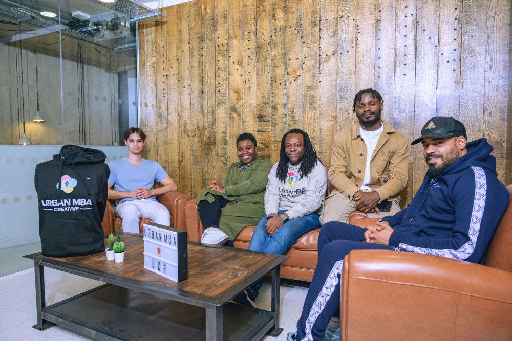 A group of people sitting together around comfortable chairs and sofas.