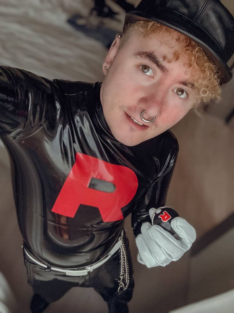 A photo of a man wearing a latex team rocket uniform