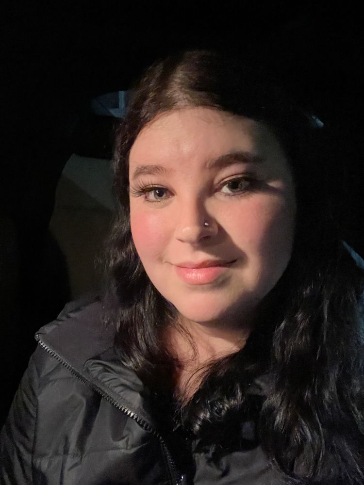 Laura is wearing makeup and posing in her car. 