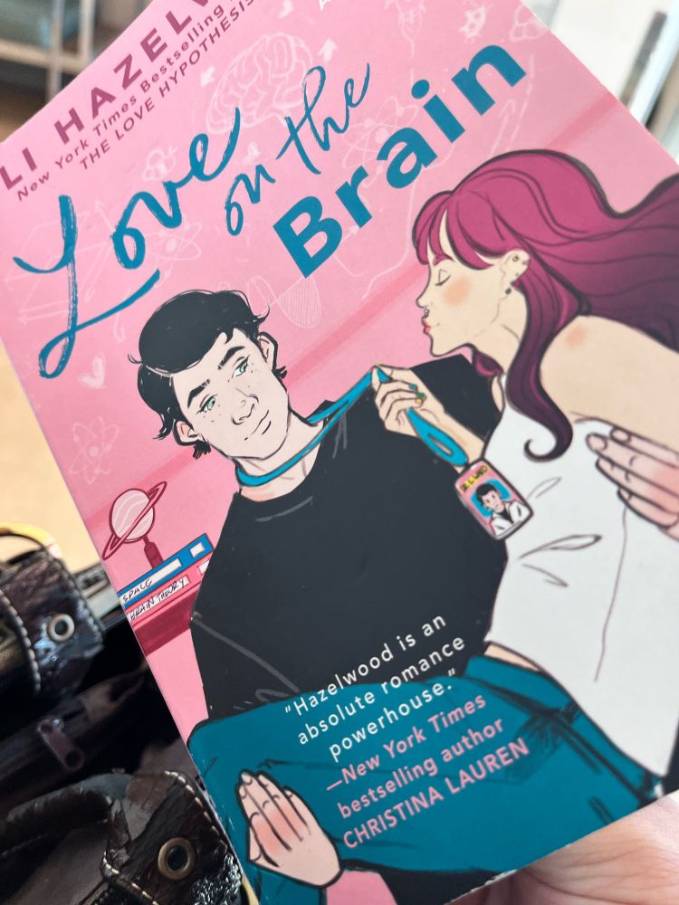 Cover of « Love on the Brain »: a dark-haired man holding a pink-haired woman, damsel in distress-style.