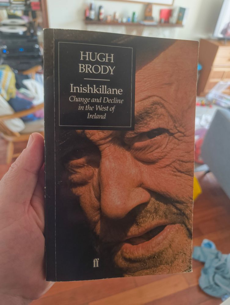 A hand holding a copy of the book "inishkillane: change and decline in the west of Ireland' by Hugh Brody