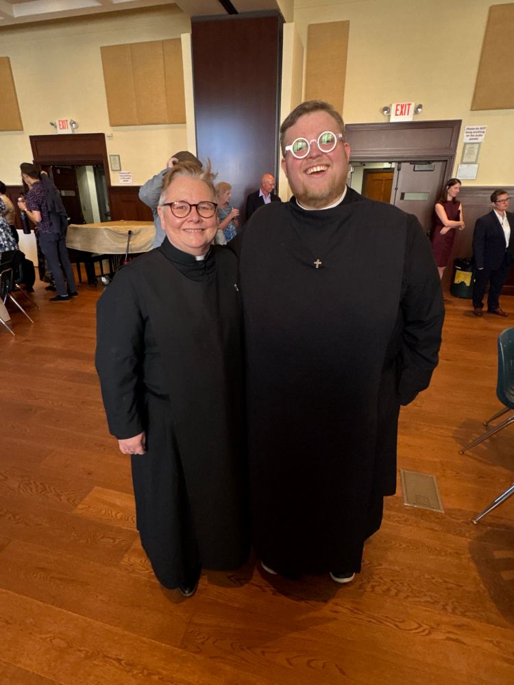 Kara and me standing in the parish hall wearing our cassocks, scapulars, and OGS pins 