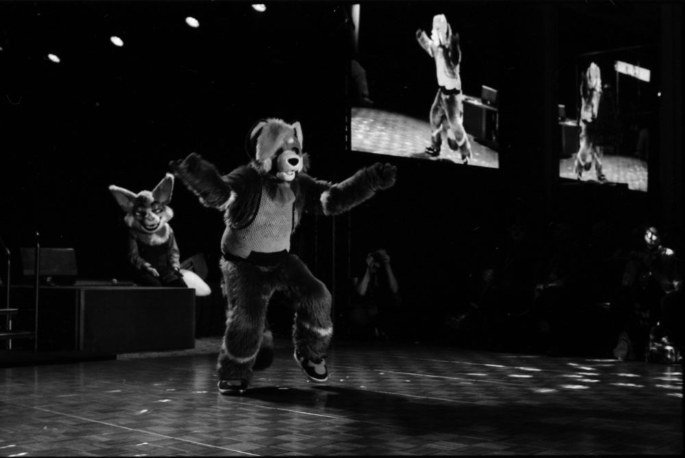 Black and white photo of Scooter dancing, arms out, one foot up