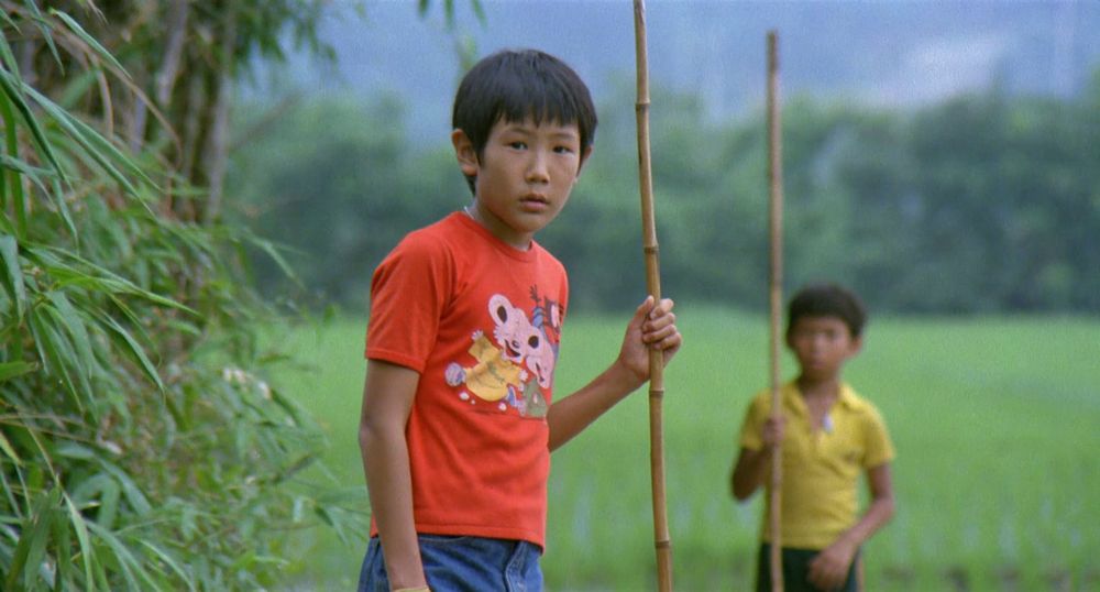 A still from a Summer at Grandpa’s (Hou Hsiao-Hsien, 1984). Tung-Tung holds a bamboo stick with his pal in the background.