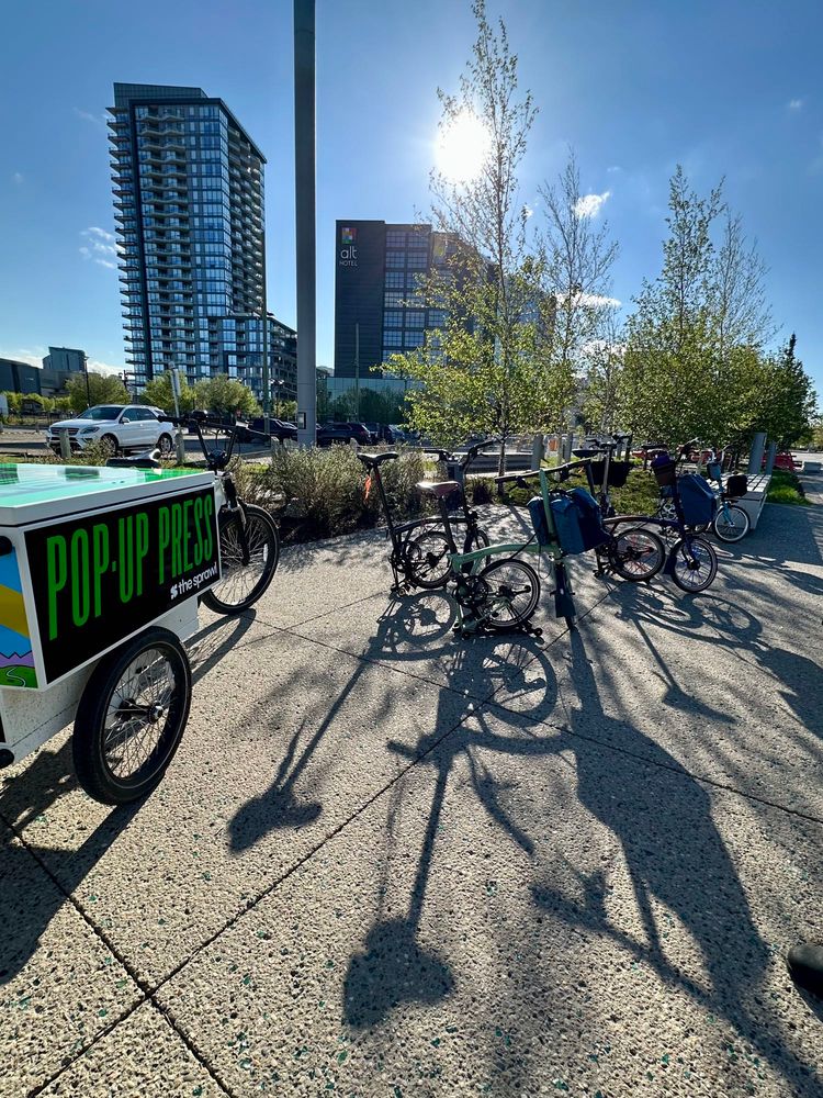 Brompton bicycles folded with their long shadows on the pavement. 