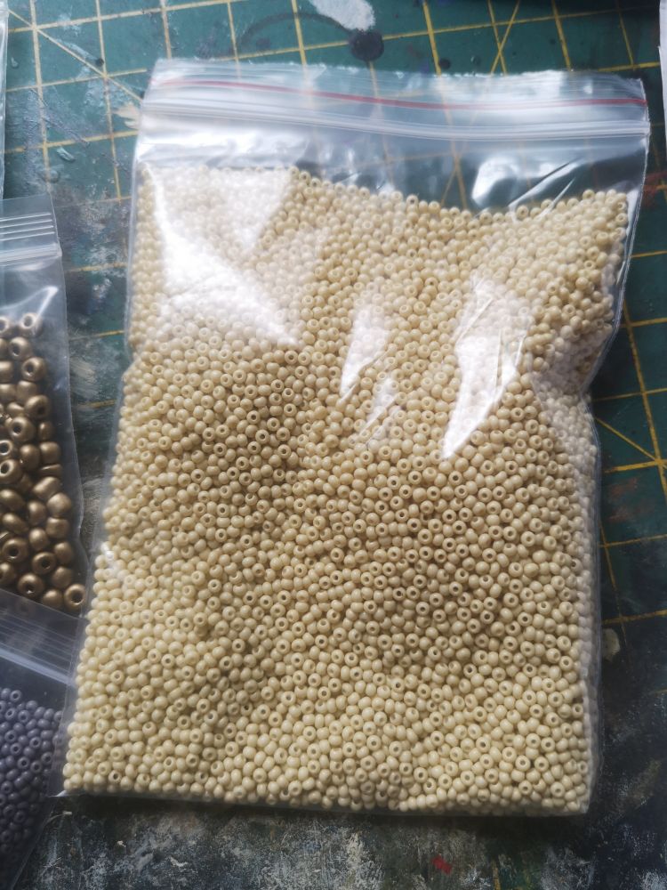 Transparent plastic bag full of tiny beige colour beads
