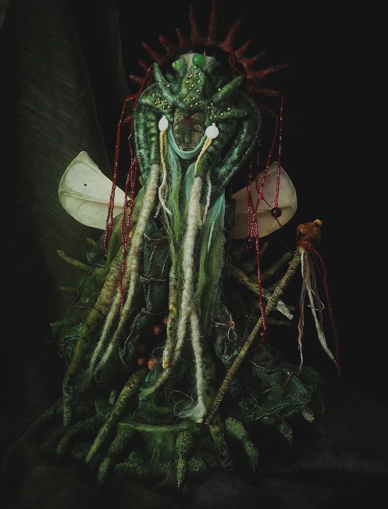 Photo of a mixed media doll made from fabrics, bones, wood and wire. Grotesque and macabre in shades of green with red accents and lots of texture.