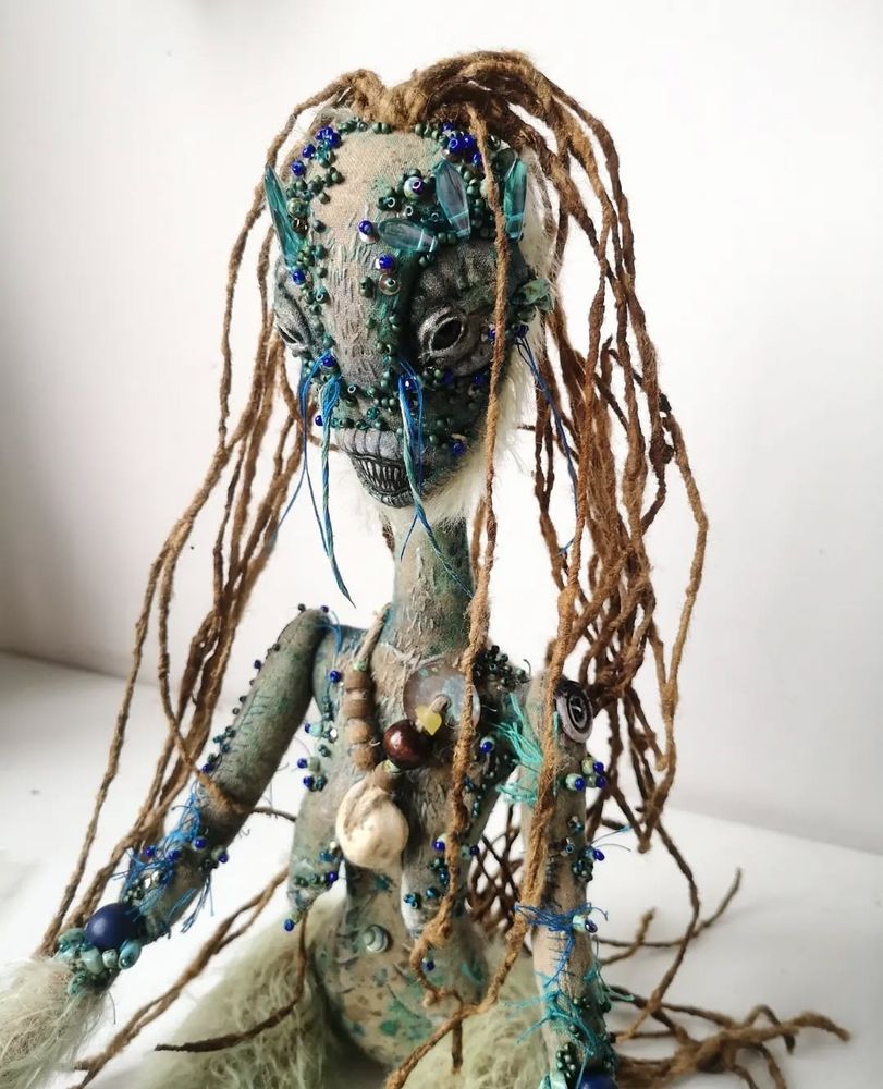 Photo of a textile art doll, a 'sea hag' highly textured with paint and beading, fur and silk yarn