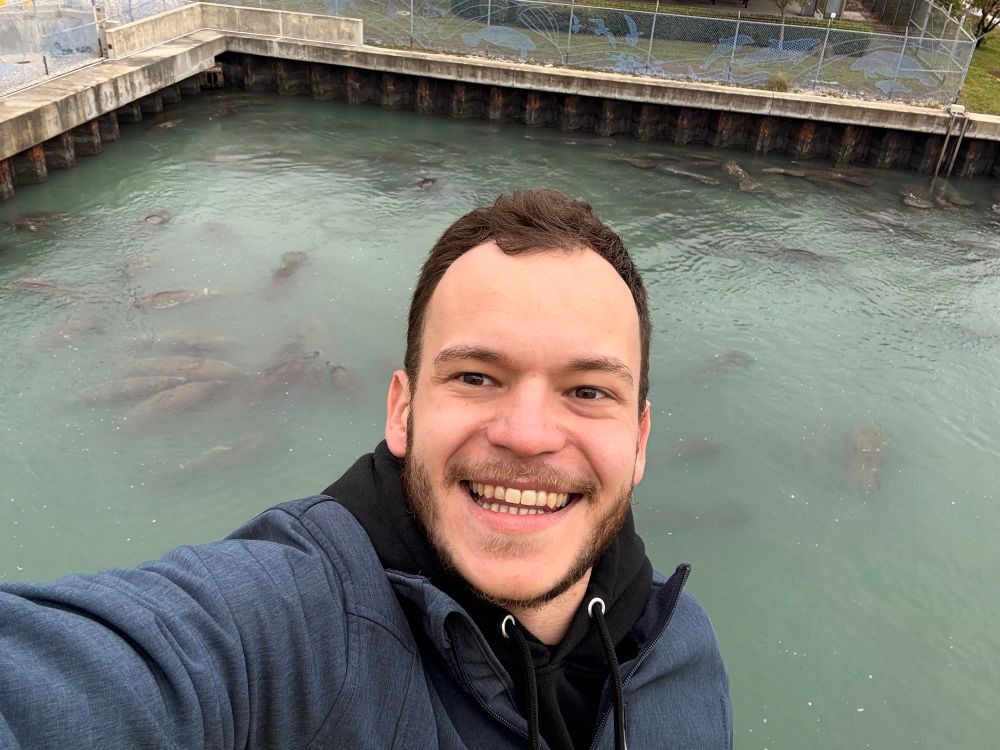Selfie von mir, im Hintergrund ein Becken in dem sich viele Seekühe tummeln