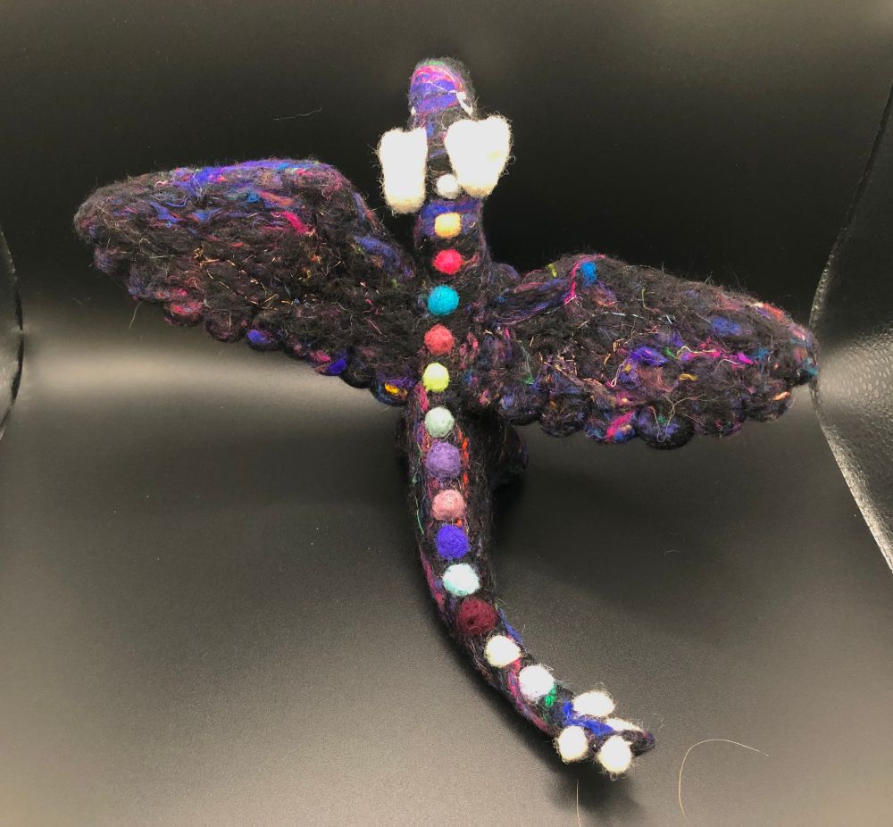 Photo of a needlefelted dragon made of multicolor dark wool with shiny accents.