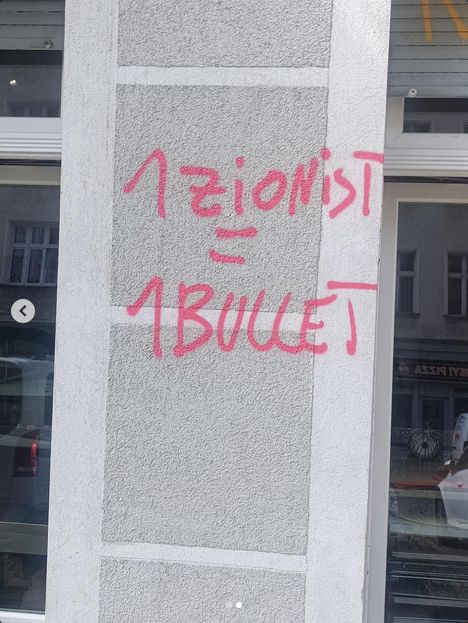 Eine Säule, dahinter Glasvitrinen von Geschäften o.ä.. Auf der Säule steht gleiches wie im ursprünglichen Post in rot geschrieben bzw. gesprüht: "1 Zionist = 1 Bullet".