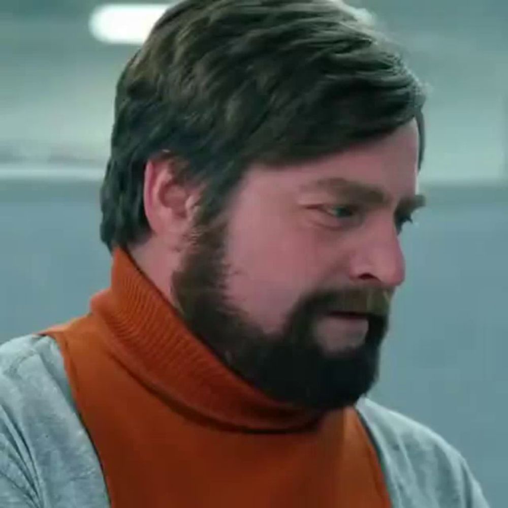 a man with a beard is wearing a turtleneck sweater and a scarf .