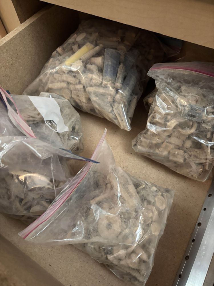 Miscellaneous bolts, washers, screws, bullet cases, bottle caps, and other desert detritus lie in a drawer, sorted into dusty ziploc bags according to form and function.