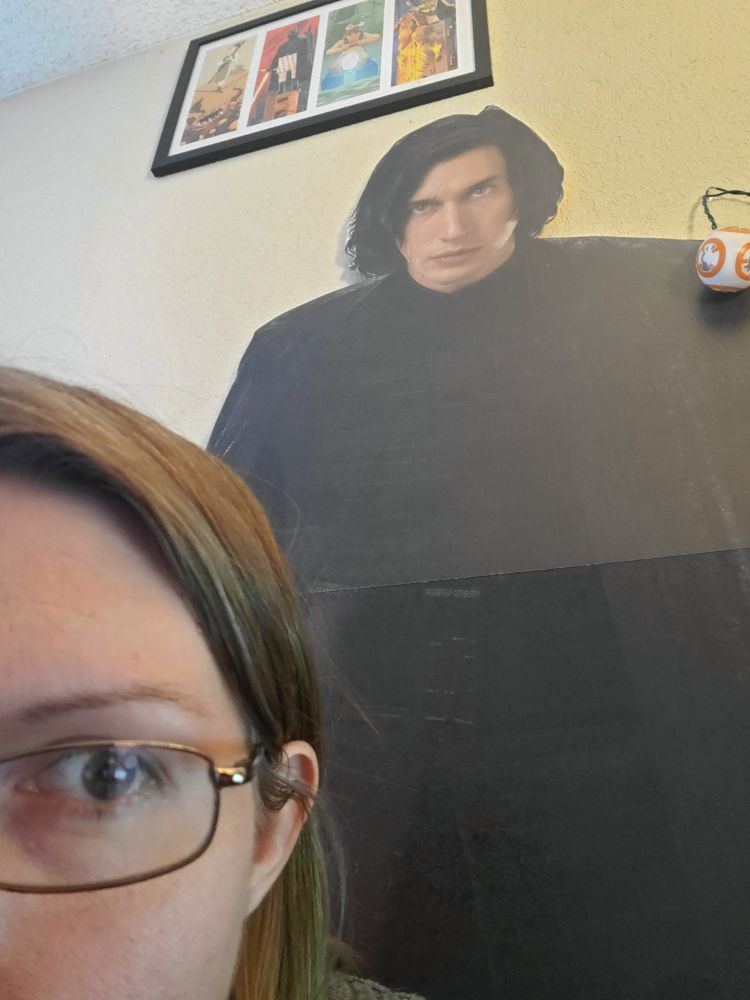 Photo of me peeking out from the corner, with my cardboard cutout of Kylo Ren behind me. 