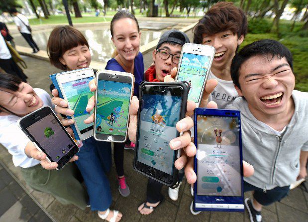 group of people smiling showing their phone screens with pokemon go