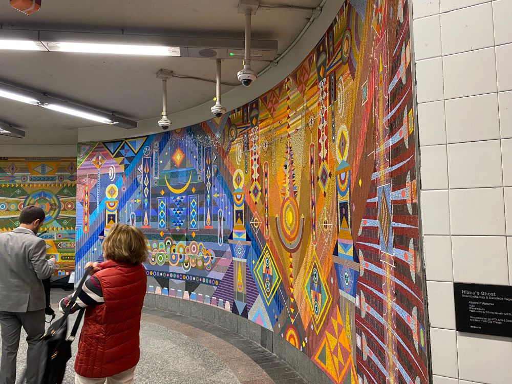 A colorful mosaic decorates the wall of a subway entrance area 