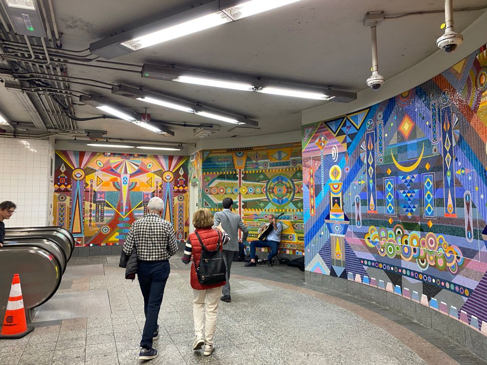 A rounded hallway is covered with colorful tiles in different geometric shapes and patterns