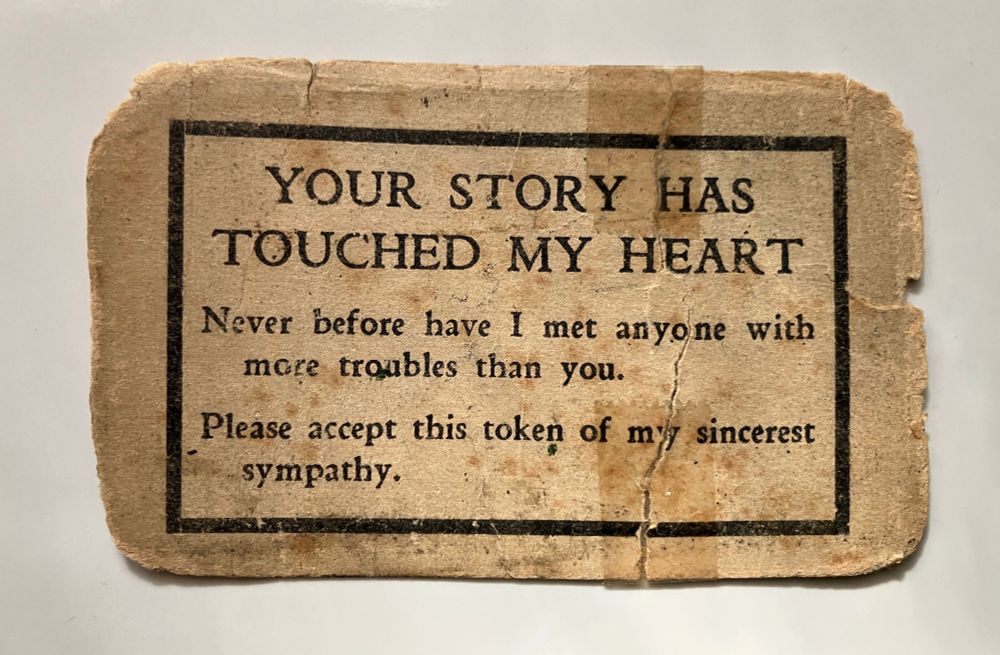 A yellowed and very worn paper card that has been taped back together:

YOUR STORY HAS 
TOUCHED MY HEART

Never before have I met anyone with
     more troubles than you. 

Please accept this token of my sincerest
     sympathy. 
