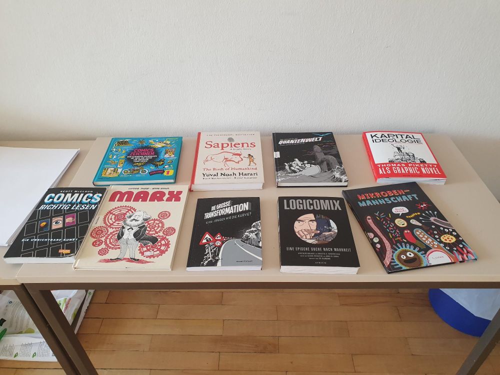 Zu sehen sind verschiedene Wissenschaftscomics auf einem Tisch.