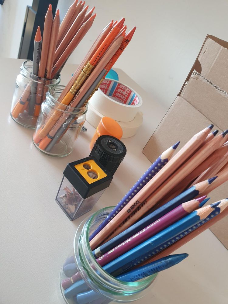 Zu sehen sind Zeichenutensilien auf einem Tisch angerichtet.