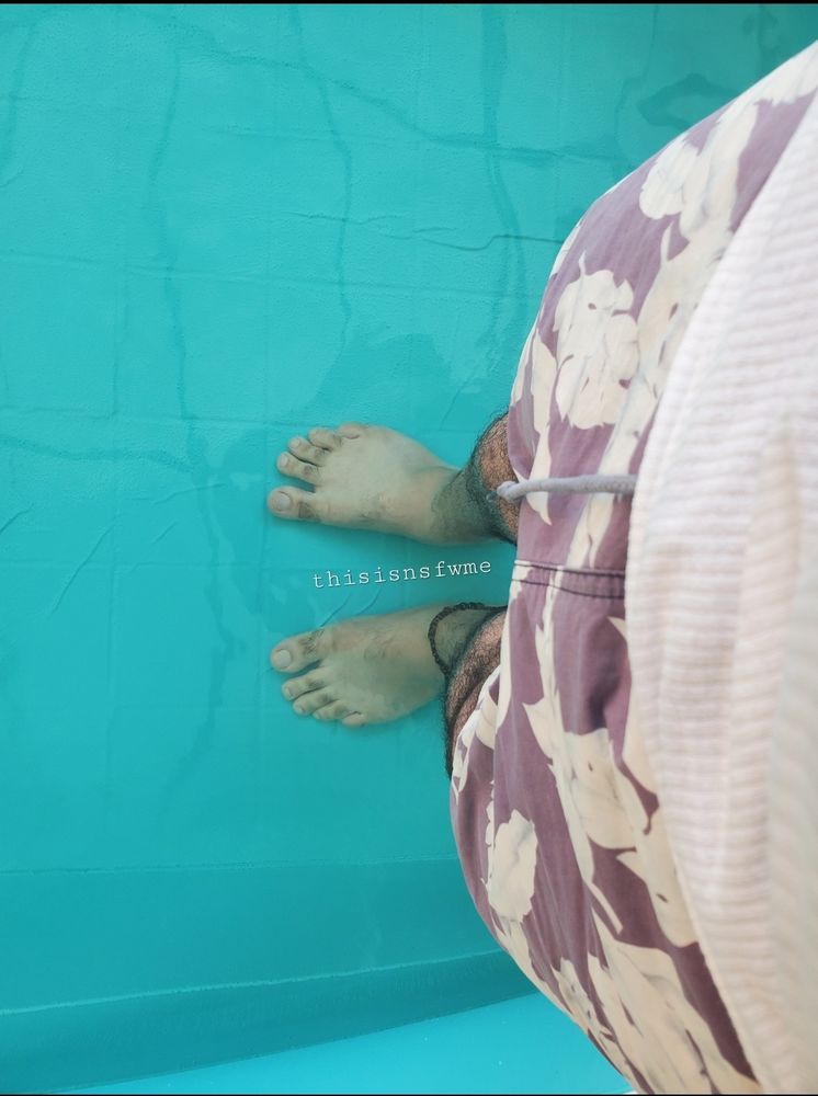 Size 13 male feet in a pool. Legs in blue flower shorts. Watermarked with thisisnsfwme 