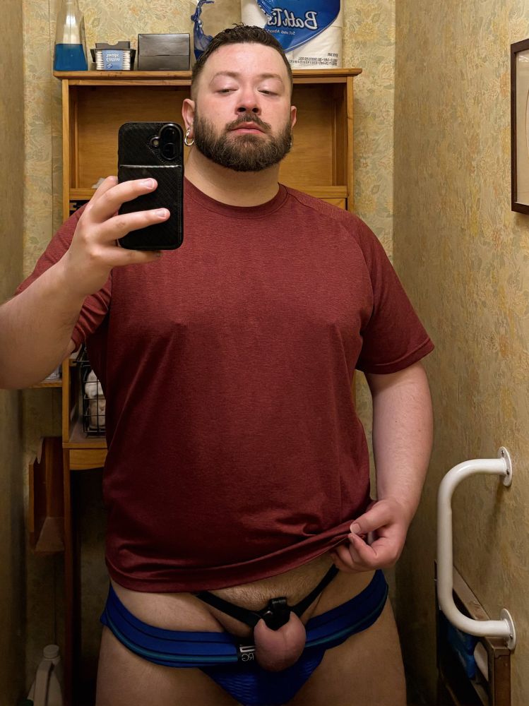 Another mirror selfie featuring a horny gay bear recently having choked on Sir’s large dick; I’m pulling up my red t-shirt to show off my inverted locked nub and lightly abused balls, like a good boy