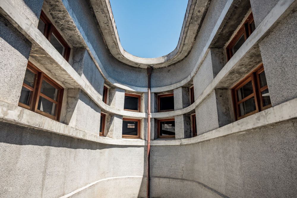 The central courtyard in a Japanese colonial era wet market showing grey pebble-washed walls and small glass and wood windows.