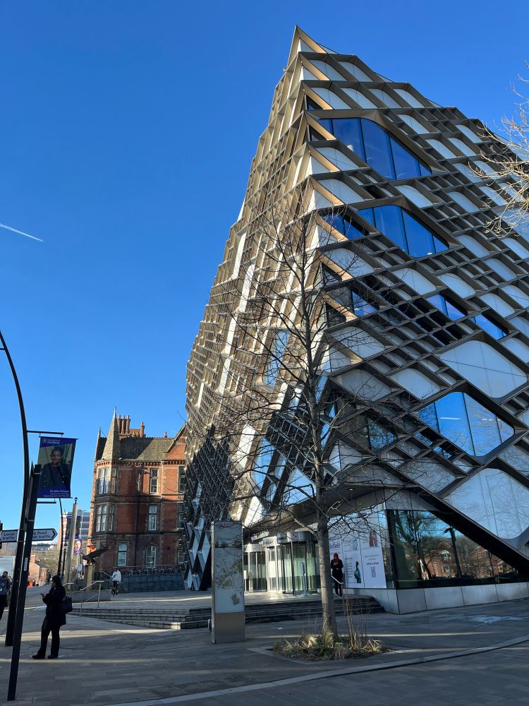 Building, with diamond shaped windows covering all sides, on the right (The Diamond Building at the University of Sheffield) with a blue sky on the left