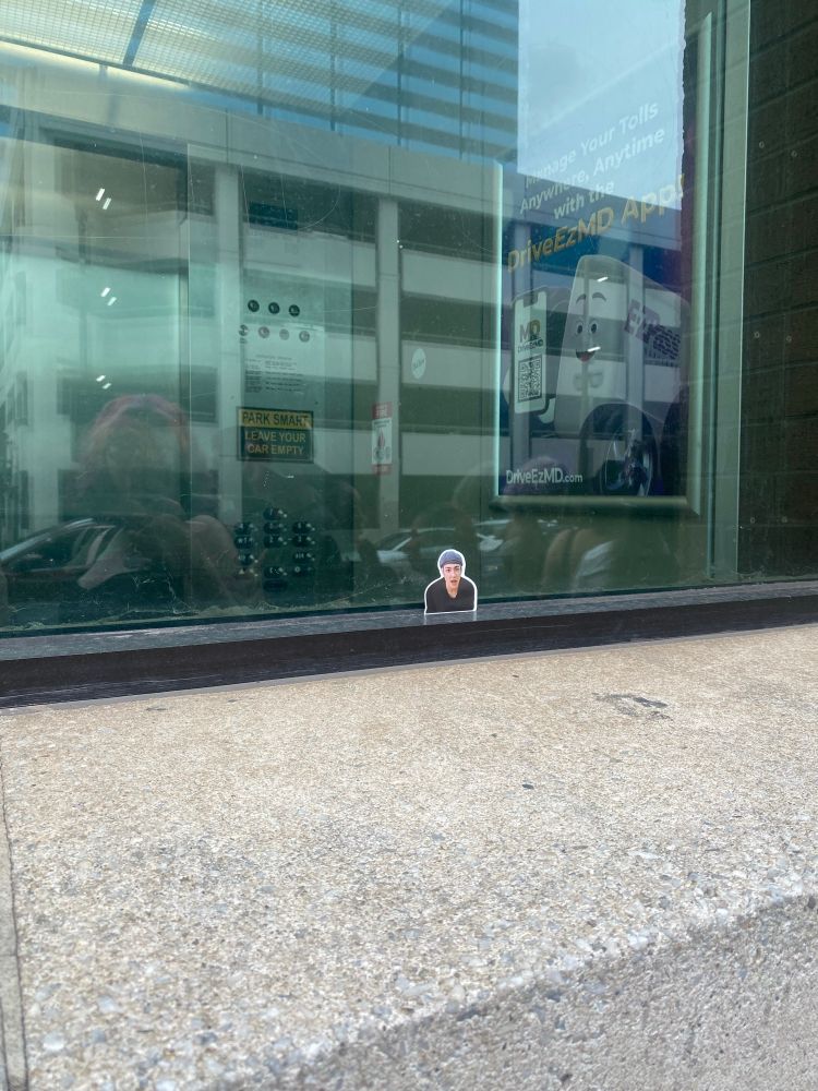 A tiny sticker of Hongjoong from ATEEZ that someone placed in the window of a parking garage near CFG arena