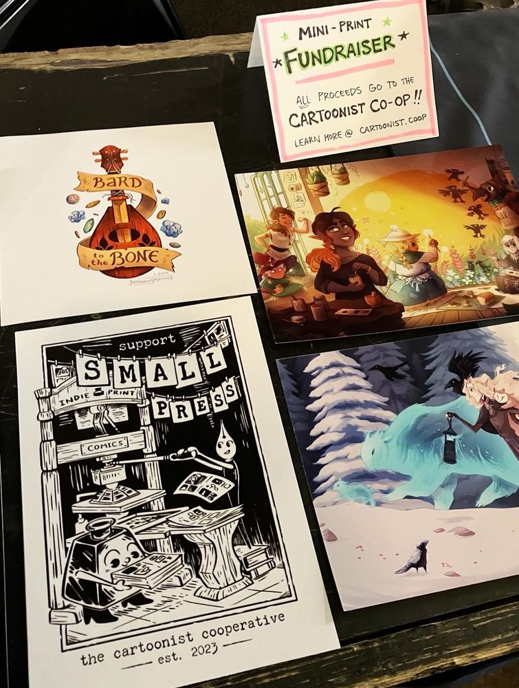 A table of prints with a fundraiser for the cartoonist cooperative
