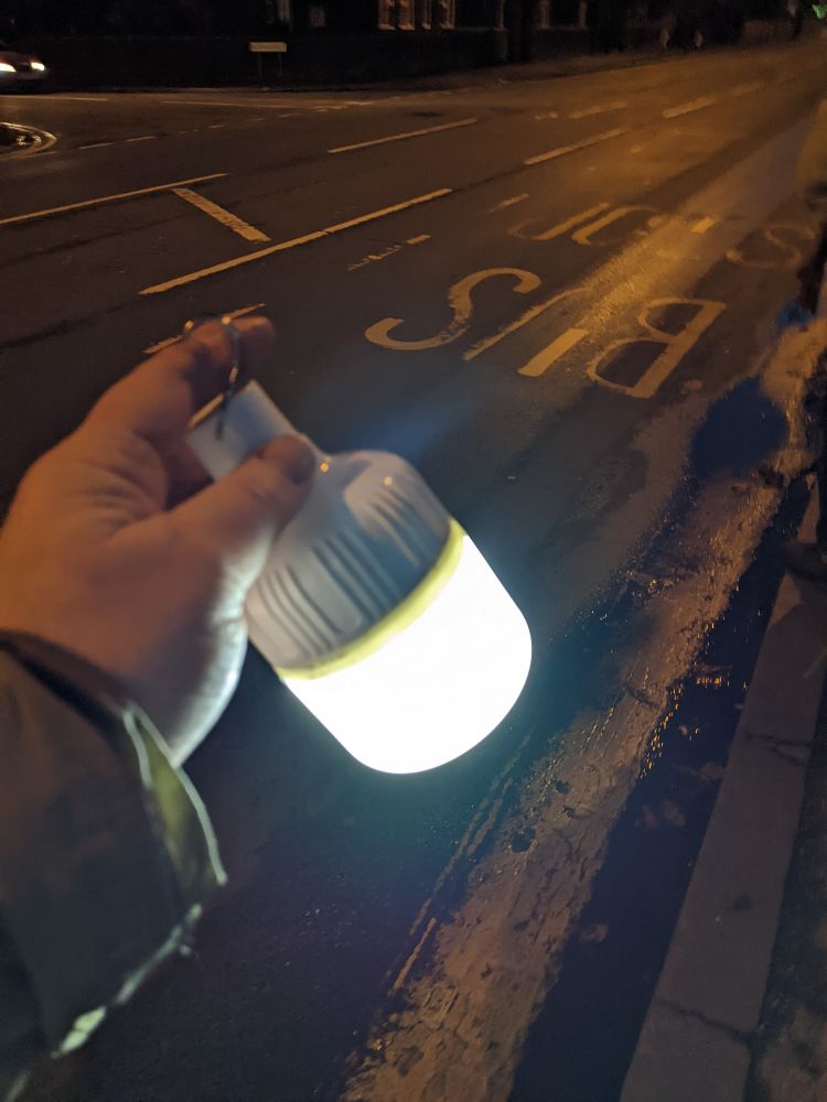 A hand holding an led lantern in the dark at a bus stop in Birmingham 