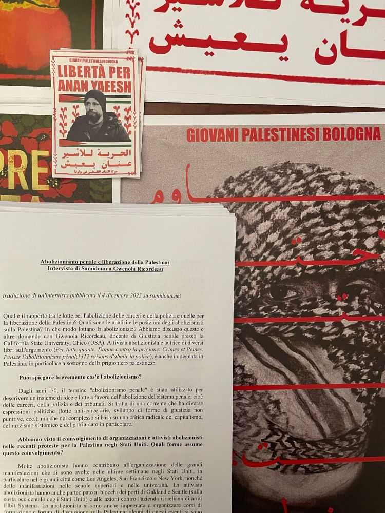 avec en arriere plan des affiches ou stickers dont "Liberta per anan yaeesh", un document avec un texte en italien