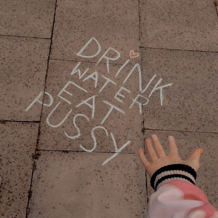 Auf einem Gehweg aus braunen Steinplatten steht mit weißer Kreide geschrieben: „DRINK WATER EAT PUSSY“. Eine kleine, ausgestreckte Hand mit einer rosafarbenen Jacke ist am unteren rechten Bildrand zu sehen. Über dem Wort "DRINK" ist ein kleines Herz gemalt.

Pic ist ein Netzfund 

